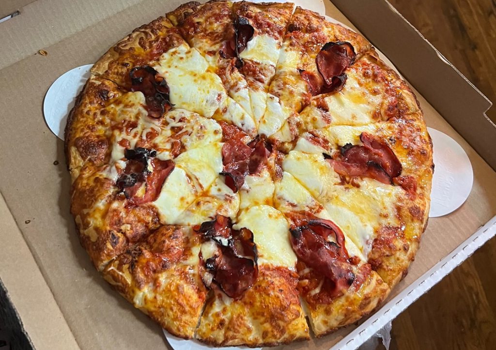 close-up of old school pizza and wings pizza inside of pizza box