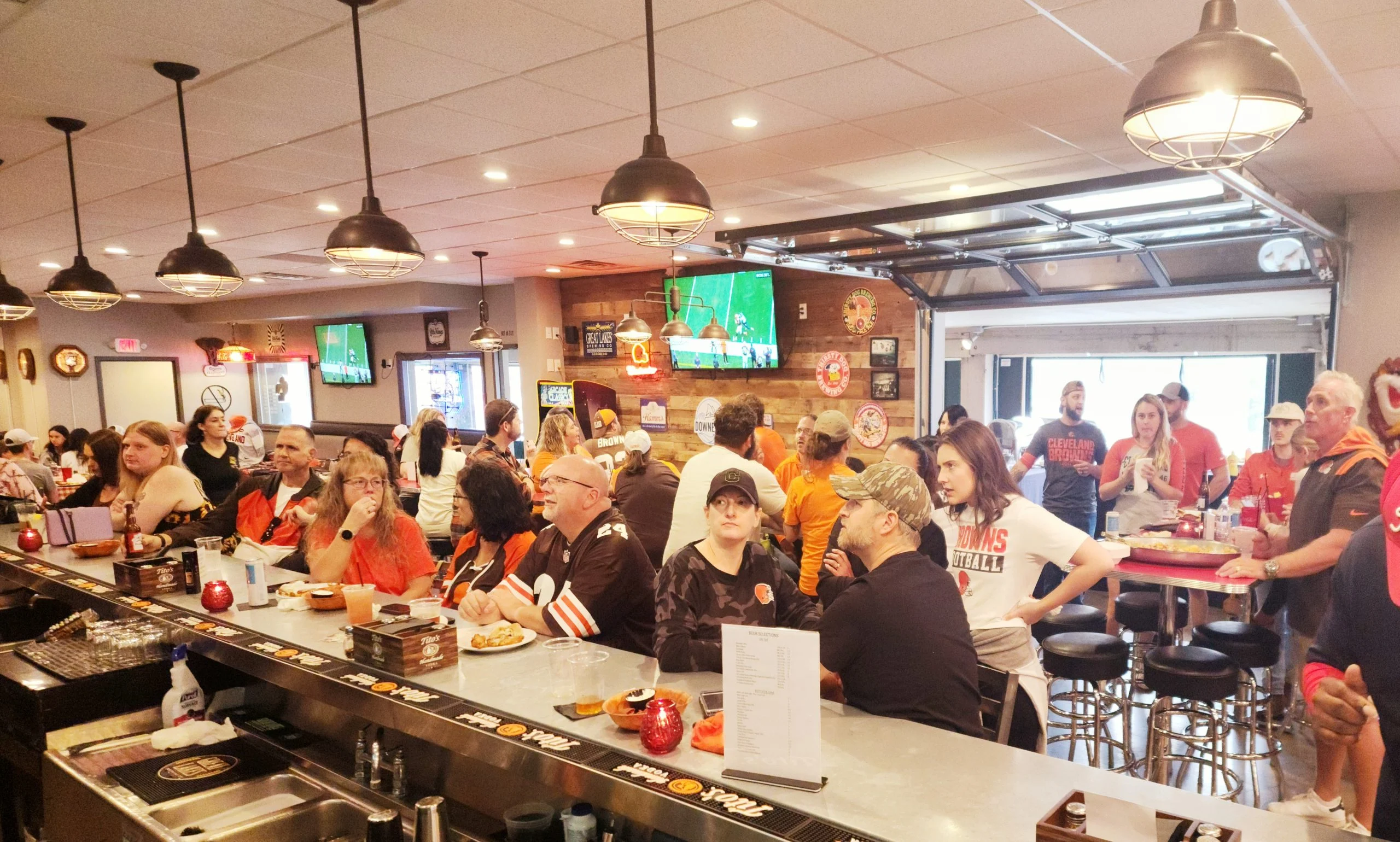 multiple people watching browns game inside of old school pizza