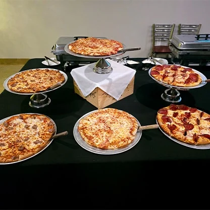 Multiple pizzas on catering table